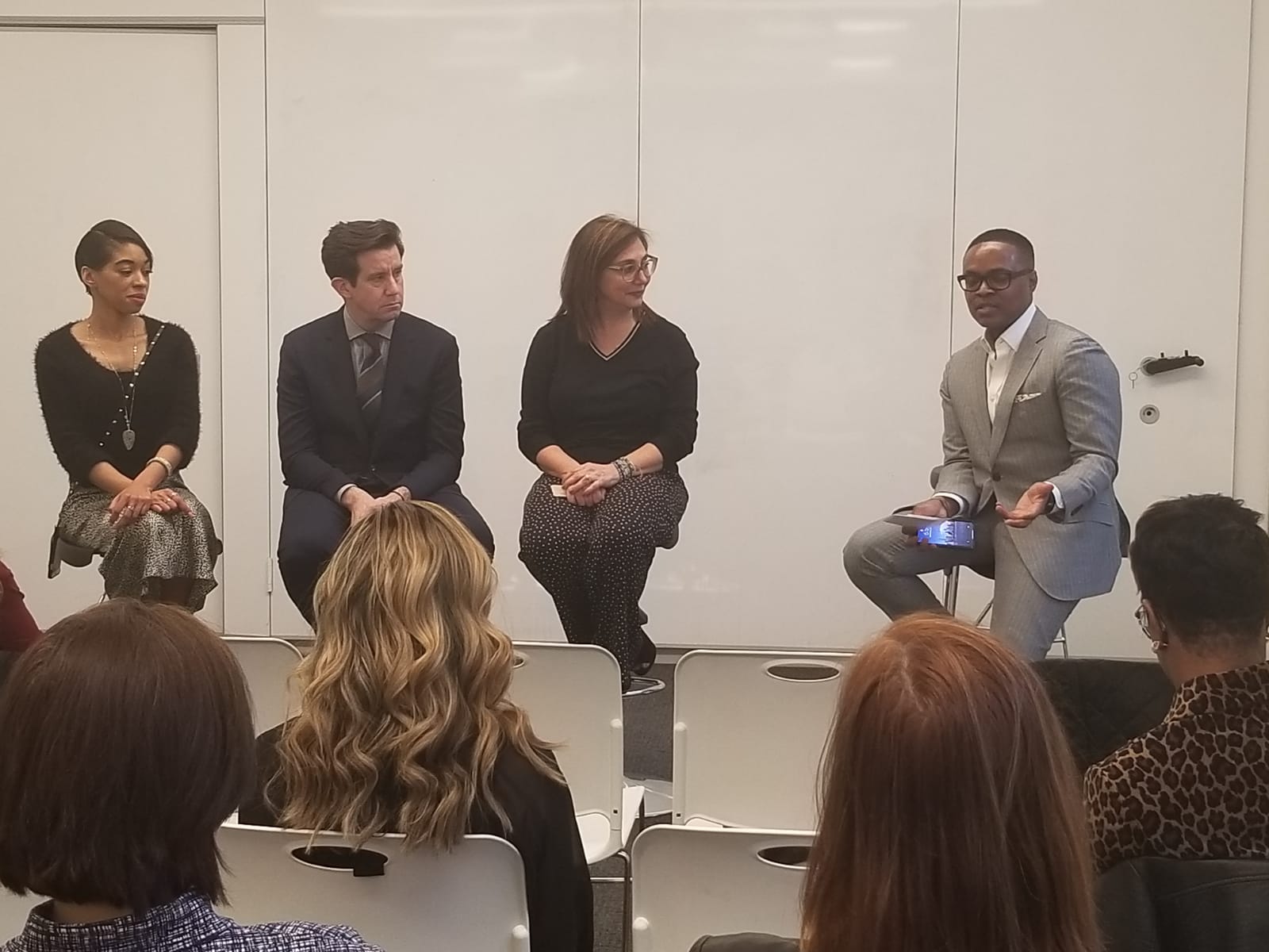 David McKnight speaking on a panel discussion in a light grey suit