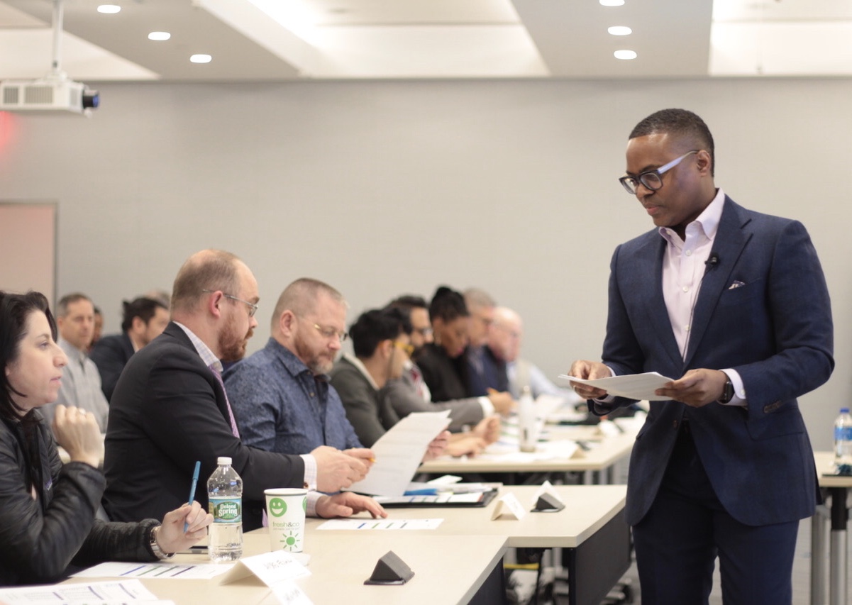 David McKnight in a navy suit reading notes while leading a workshop table